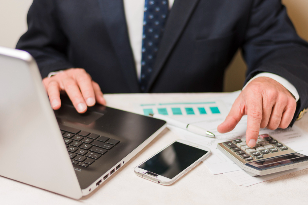 man using calculator and a laptop